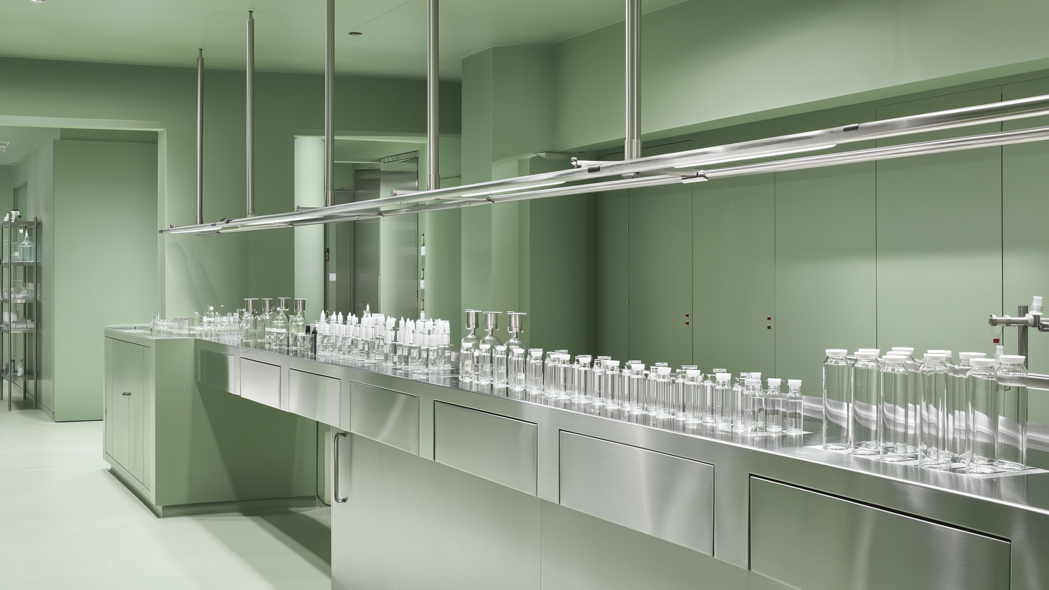 Clean modern pharmaceutical laboratory with stainless steel surfaces and glass vials in sage green and white tones
